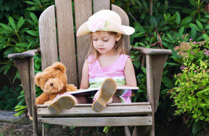 Little girl pretending to read to her teddy bear